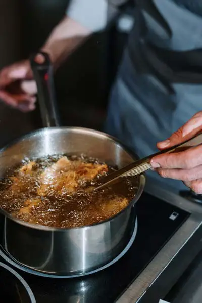 A person cooking with a stainless steel saucepan