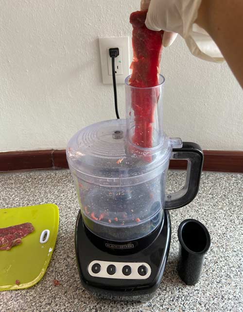 Put the meat through the feeder tube of the Food Processor