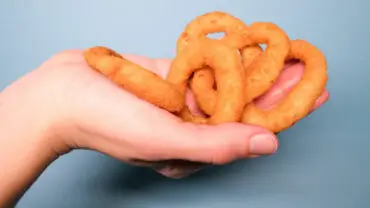 Hand holding golden, deep fried onion rings