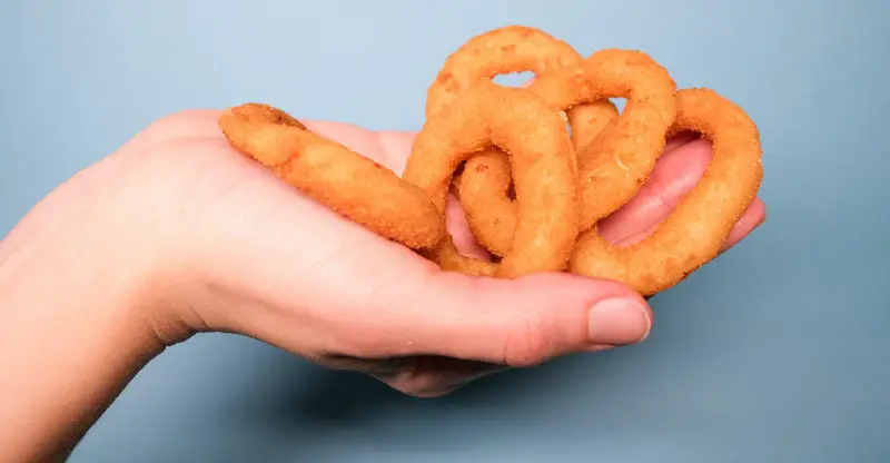 Hand holding golden, deep fried onion rings