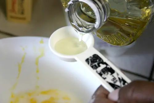 Close-up of measuring oil into a tablespoon.