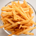 Top view of golden french fries in a glass, sprinkled