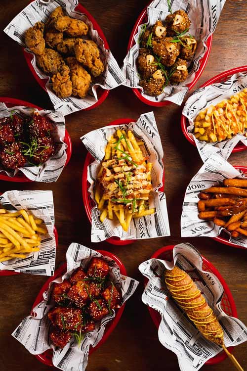Wings, hotdogs, and fries in red baskets on top of a wooden table