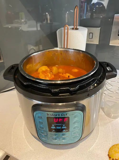 Instant Pot Duo Mini with chicken, potatoes, and tomato sauce inside the chamber