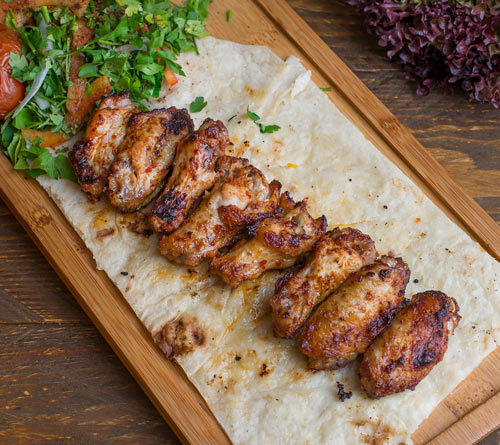 Roasted chicken cuts marinated with rubs on top of pita