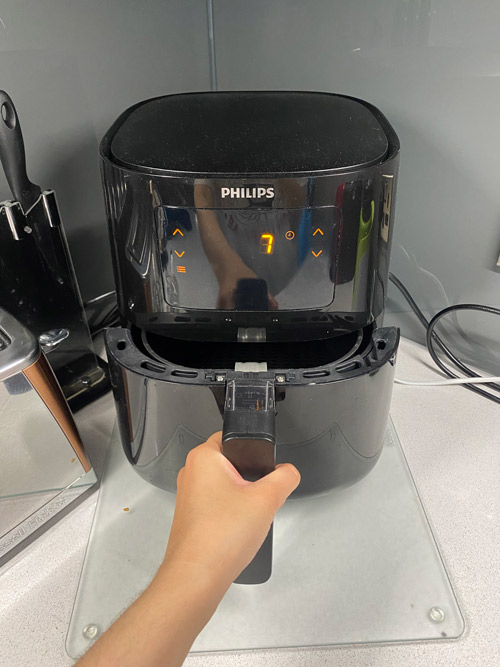 Someone closing the Philips air fryer with the time and temperature set for preheating
