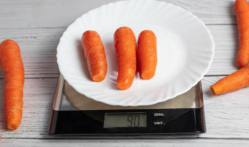 Three carrots on a kitchen scale